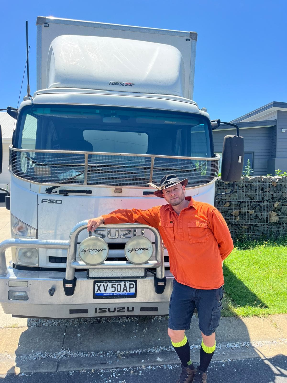 Ariel Raz, owner of Ready To Move, in his orange hi-vis shirt at the front of his Isuzu truck in Mullumbimby